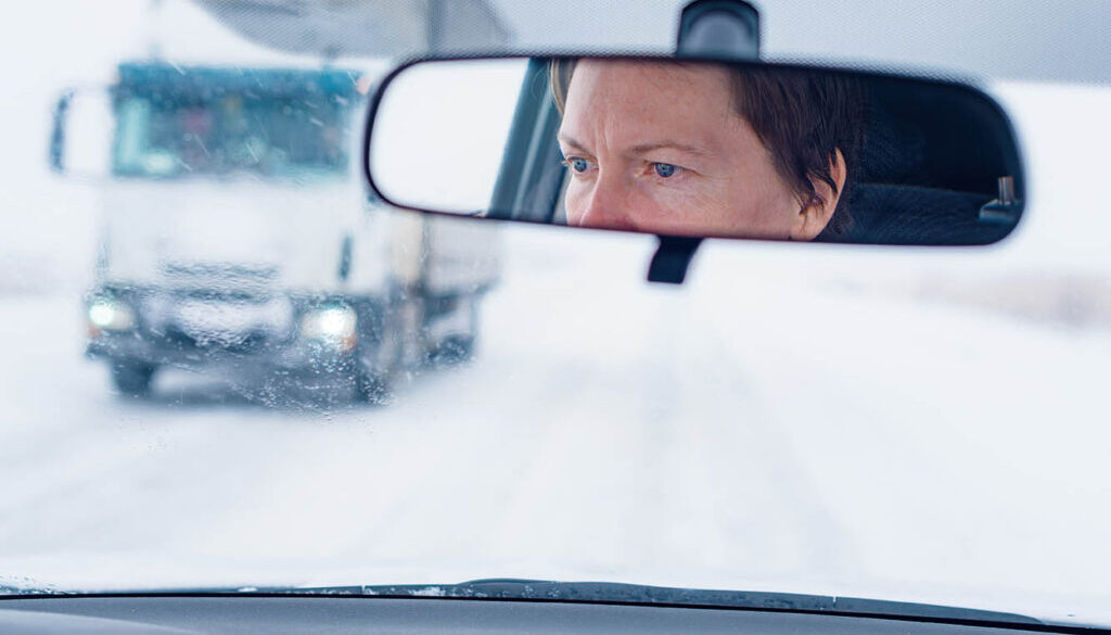 Face of a female driver in car rear-view mirror while driving in