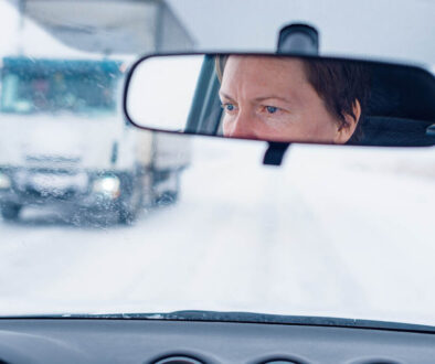 Face of a female driver in car rear-view mirror while driving in